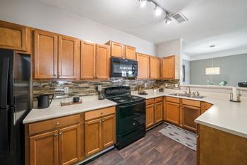 Spacious Kitchen with Black Appliances and ample storage located at Sugarloaf Crossings Apartments in Lawrenceville, GA 30046